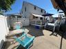Private concrete patio with a raised wooden deck, white privacy fencing, and exterior siding
