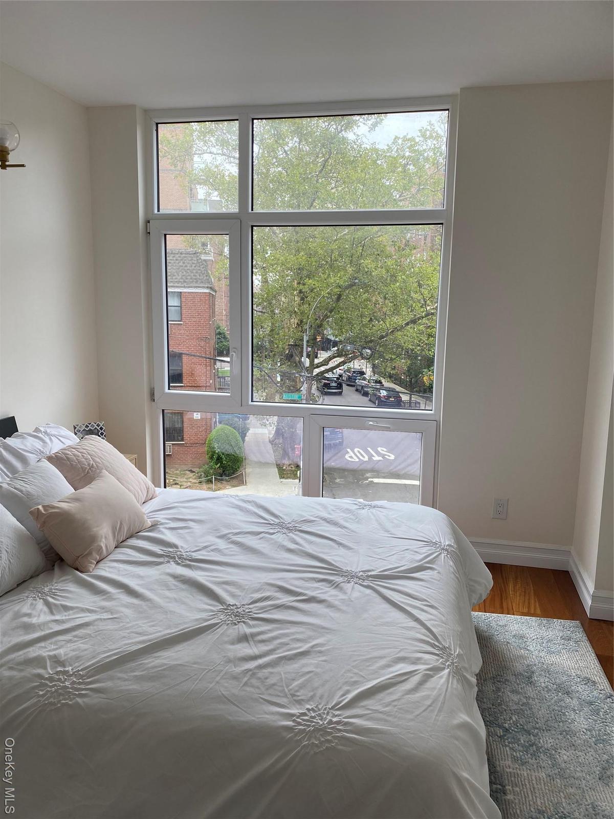Bedroom with wood finished floors and multiple windows