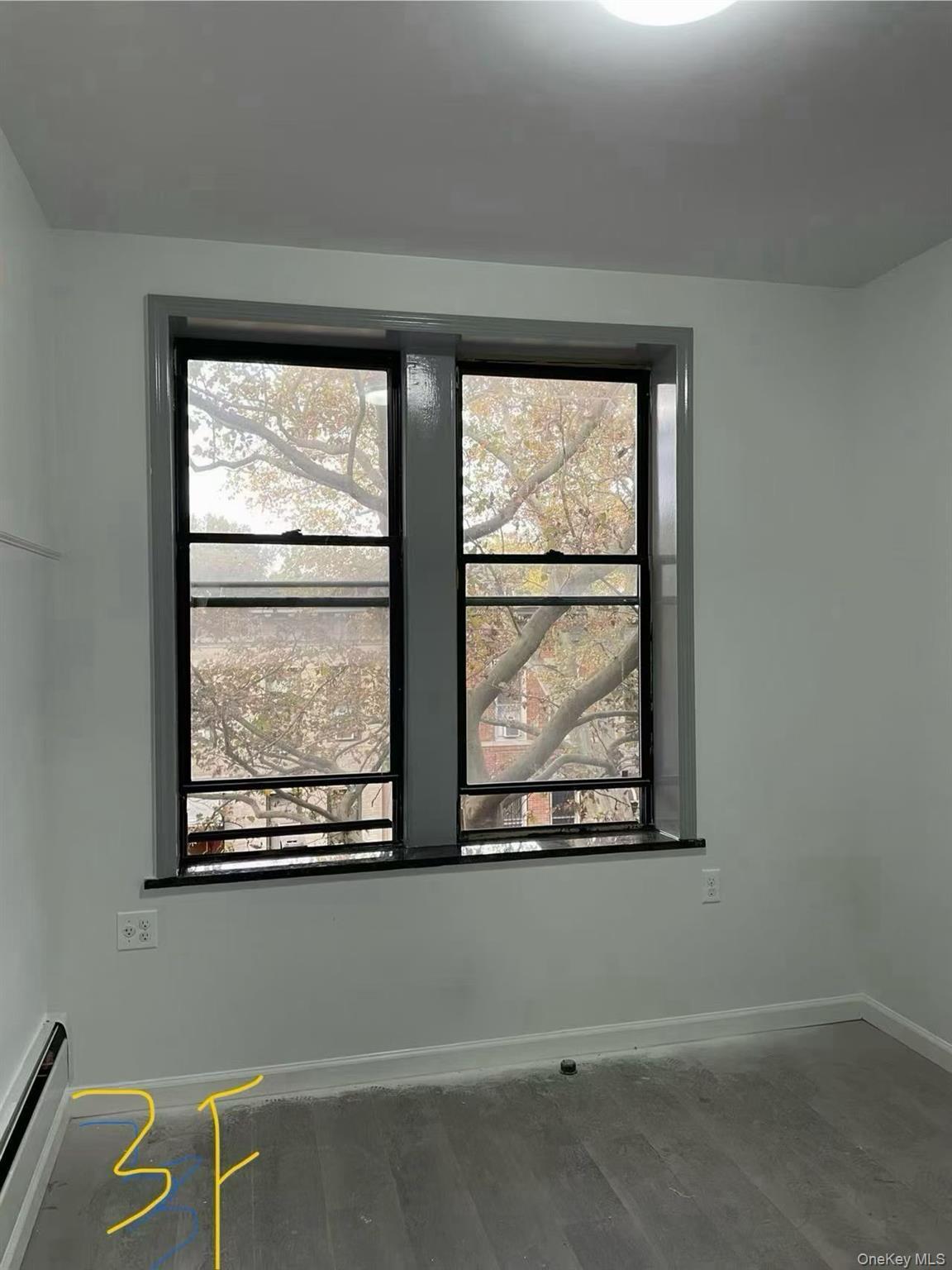 Empty room featuring a baseboard radiator and wood finished floors