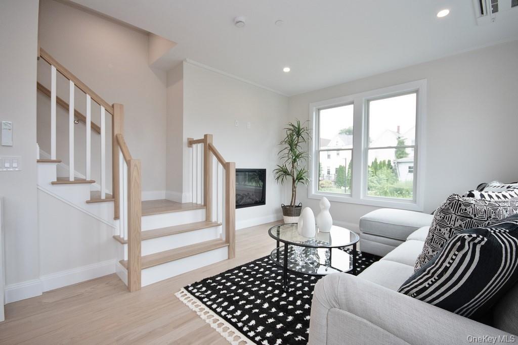 Living room featuring light wood-type flooring, recessed lighting, a premium fireplace, and stairs