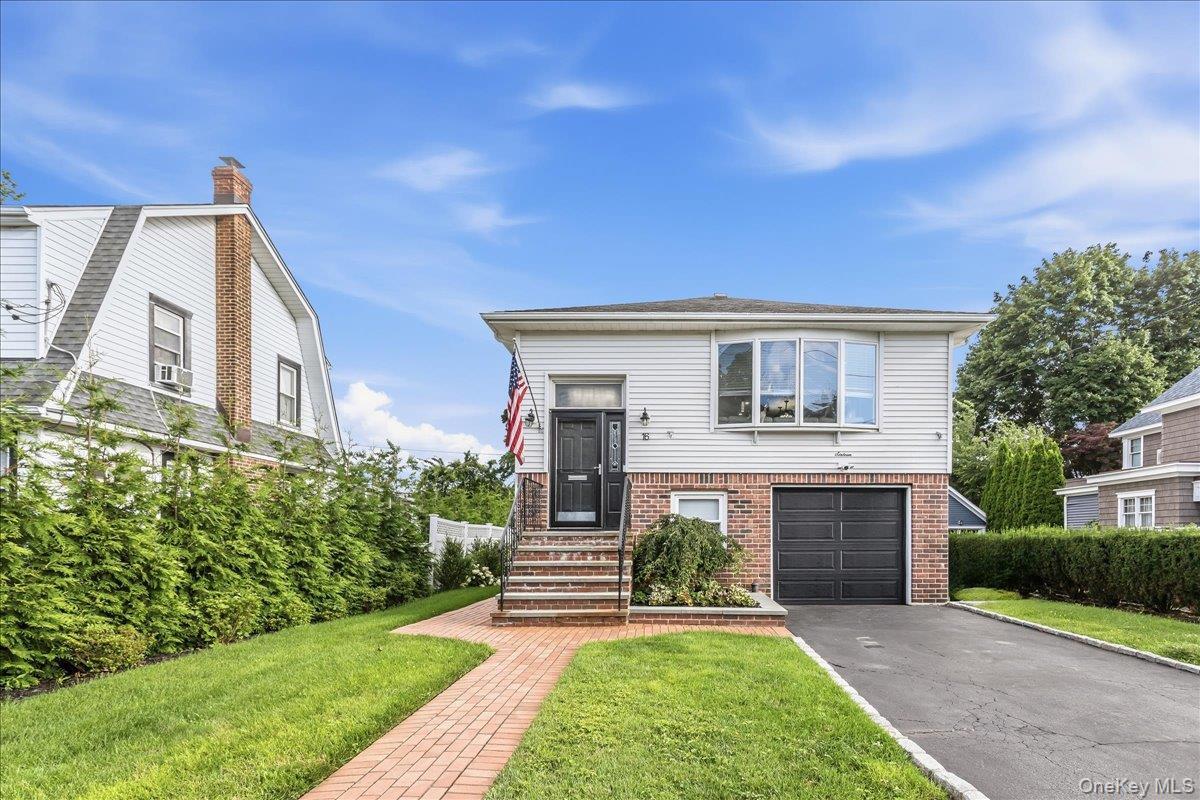 Contemporary residence featuring a brick walkway, manicured lawn, and an attached garage