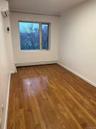 Empty room featuring wood-type flooring, a wall unit AC, and a baseboard heating unit