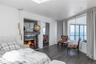 Bedroom featuring a water view, a warm lit fireplace, and wood finished floors