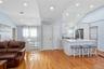 Kitchen featuring vaulted ceiling, a kitchen breakfast bar, white cabinetry, open floor plan, and light wood-type flooring