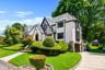Tudor-style residence featuring a prominent front gable, stucco and half-timbering accents, a stone-clad foundation, and a slate-tile roof