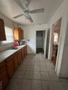 Kitchen featuring tasteful backsplash, light countertops, ceiling fan, light tile patterned floors, and brown cabinets