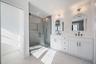Spa like primary bath featuring a freestanding soaking tub, oversized glass shower, and modern finishes.