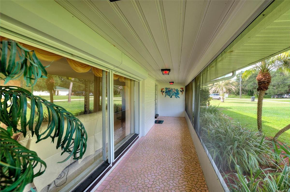 Beautiful porch with vintage broken tile. There are hurricane shutters on the big front windows.