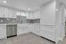 Bonus: Modern kitchen featuring white shaker cabinetry, an integrated white farmhouse sink with a gold-tone faucet, and a stainless steel dishwasher