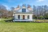 Modern farmhouse style home with a standing seam roof, a porch, a chimney, a front yard, and metal roof