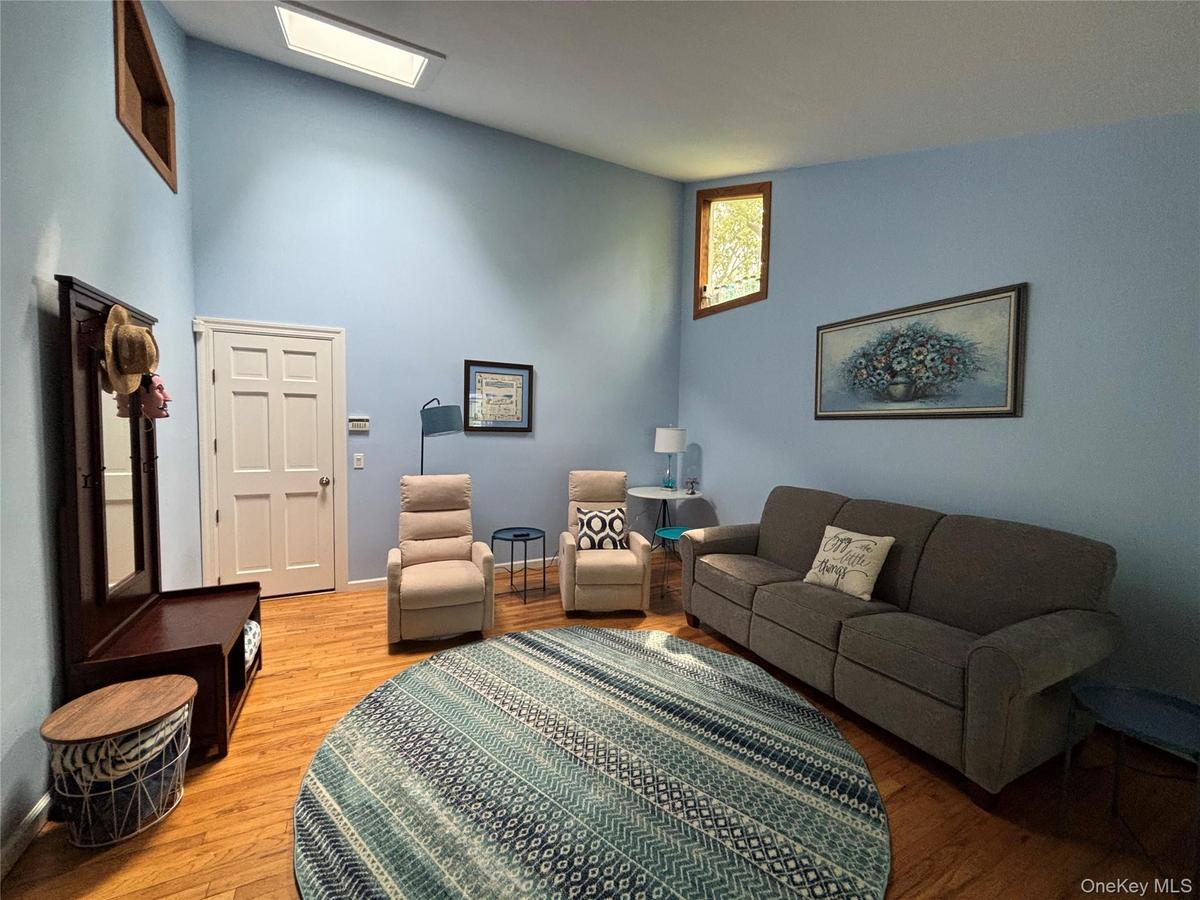 Vaulted ceiling room with natural wood-finish flooring, skylight for abundant light