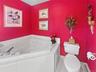 Bathroom with a tub with jets, toilet, and a baseboard heating unit