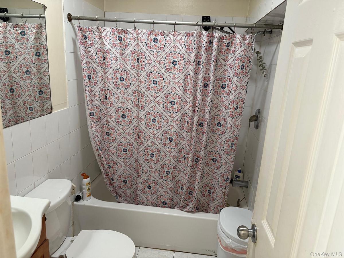 Bathroom featuring vanity, tile walls, shower / tub combo, and tile patterned flooring