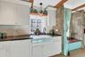 Kitchen featuring dark countertops, white cabinetry, tasteful backsplash, light wood finished floors, and decorative light fixtures