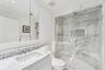 Bathroom inside primary bedroom with crown molding, custom vanity, marble finish shower, tile walls, and a stunning backsplash.