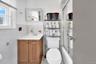 Full bathroom with tile walls, vanity, a wainscoted wall, light tile patterned flooring, and combined bath / shower with glass door