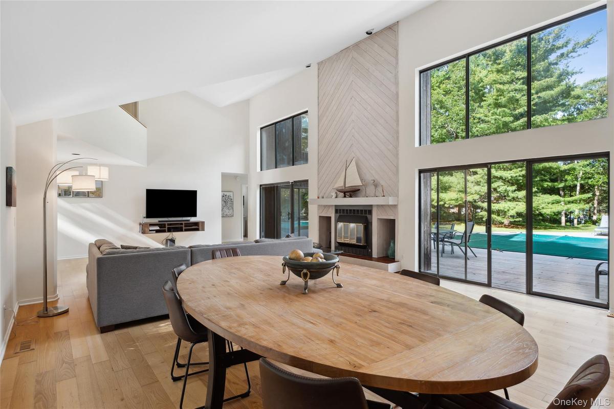 Dining space featuring a tiled fireplace, light wood-style floors, and a high ceiling