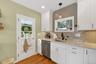 Kitchen with decorative backsplash, white cabinets, dishwasher, light stone countertops, and light wood-style flooring