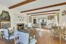 Staged Living area featuring a stone fireplace, light wood-style floors, and beamed ceiling