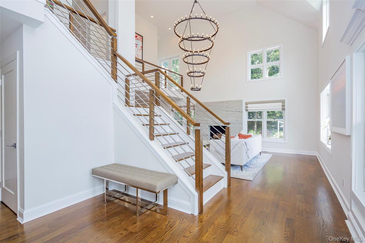 Open-concept entry foyer featuring a grand staircase with wood railings and cable balusters