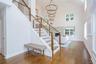 Open-concept entry foyer featuring a grand staircase with wood railings and cable balusters
