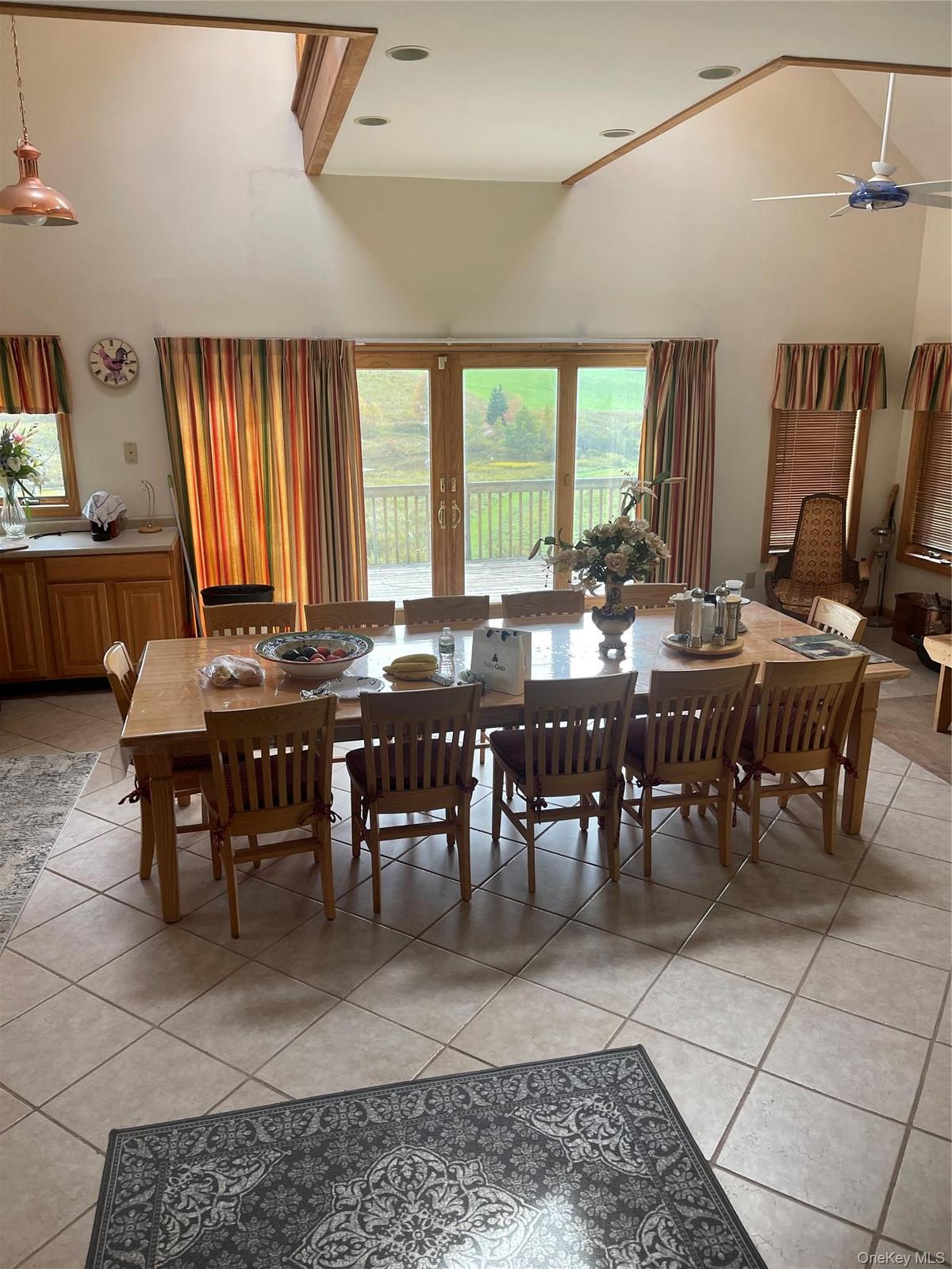 Elegant dining room showcasing vaulted ceilings with skylights, a solid wood dining table with matching spindle-back chairs, and expansive glass doors