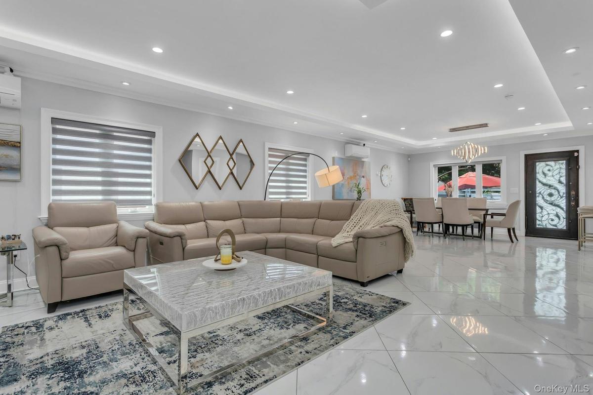 Expansive open concept living area featuring large polished tile flooring, recessed, and cove ceiling lighting, and ceiling crown and floor molding