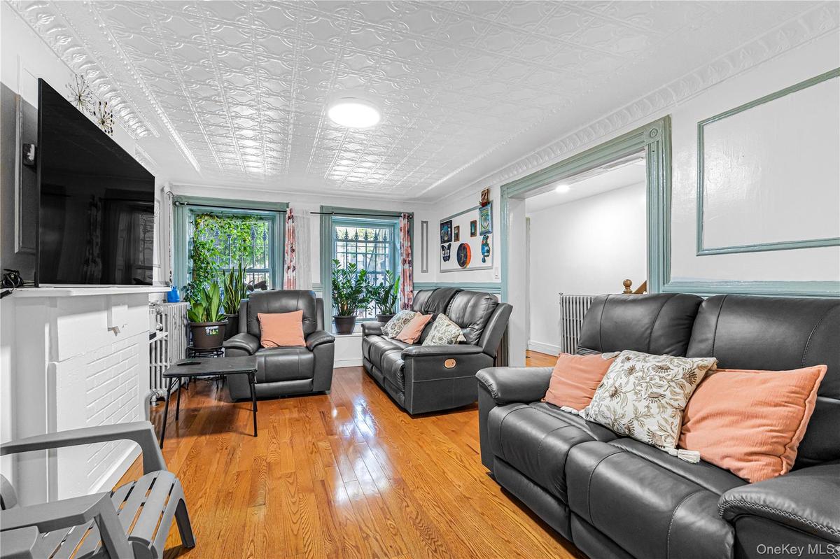 Living area featuring wood-finish flooring, an ornate white ceiling, and decorative window moldings