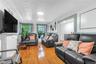 Living area featuring wood-finish flooring, an ornate white ceiling, and decorative window moldings