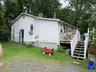 View of side of property featuring a deck, a chimney, stairway, and a yard