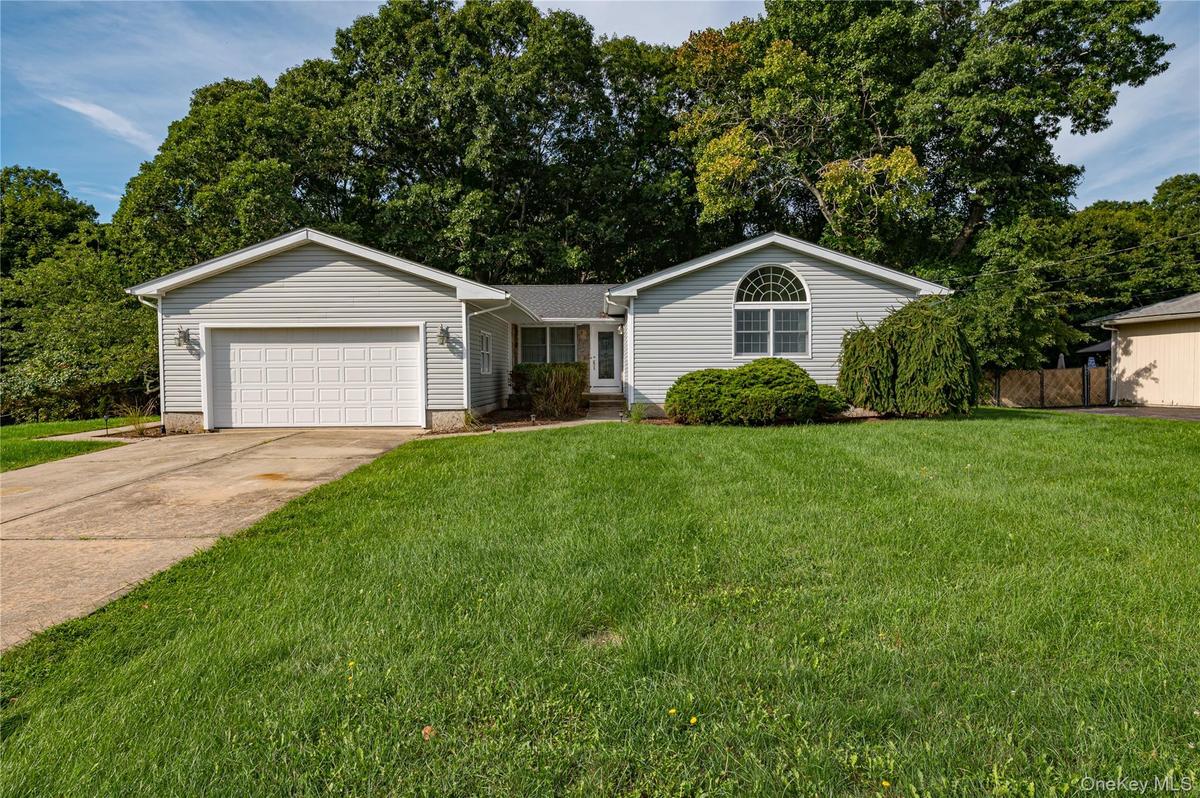 Grey vinyl siding exterior with a concrete driveway, attached garage, and a semicircular arched window