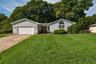 Grey vinyl siding exterior with a concrete driveway, attached garage, and a semicircular arched window