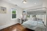 Bright bedroom featuring hardwood flooring, white trim, recessed lighting, and a double exposure.