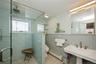 Full bath with healthy amount of natural light, a baseboard heating unit, a stall shower, and wainscoting