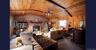 Living area featuring wood ceiling, a ceiling fan, brick wall, wooden walls, and a fireplace