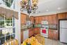 Kitchen with white appliances, tasteful backsplash, glass insert cabinets, brown cabinets, and recessed lighting
