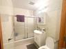 Bathroom with vanity, enclosed tub / shower combo, and tile walls