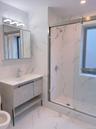 Bathroom featuring marble finish flooring, a marble finish shower, tile walls, and vanity