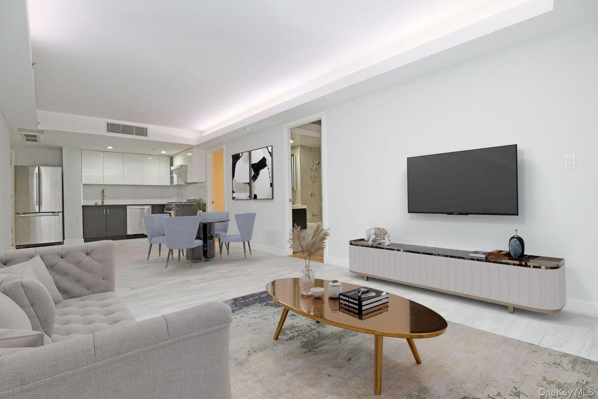 Living area with a tray ceiling, light wood finished floors, and recessed lighting