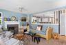 Living area featuring a fireplace with a stone surround and a white mantel, light blue walls, and Hampton decor