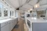 Kitchen featuring a sink, vaulted ceiling with beams, gray cabinetry, light wood-style flooring, and stainless steel appliances