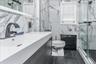 Spa-inspired primary bathroom featuring marble-look wall tile, dark tile flooring, and a floating vanity with an integrated rectangular sink