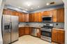Kitchen featuring wood cabinetry, stainless steel appliances, mosaic tile backsplash, and light-toned countertops