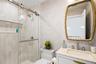 Bathroom featuring wallpapered walls, vanity, and a stall shower