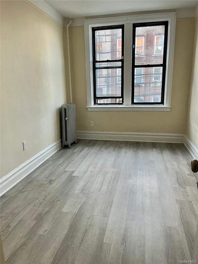 Spare room featuring radiator heating unit and light hardwood / wood-style floors