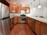 Kitchen featuring stainless steel appliances, light stone countertops, pendant lighting, a peninsula, and recessed lighting