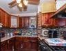 Kitchen with tasteful backsplash, range, under cabinet range hood, open shelves, and a textured ceiling