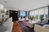Sun-filled living area with walls of windows, patio access, and picturesque views beyond