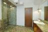 A spacious glass-enclosed shower, expansive vanity, and abundant storage complete this spa-inspired primary bath.