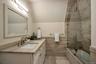 Bathroom with vanity, shower / bath combination with glass door, and vaulted ceiling